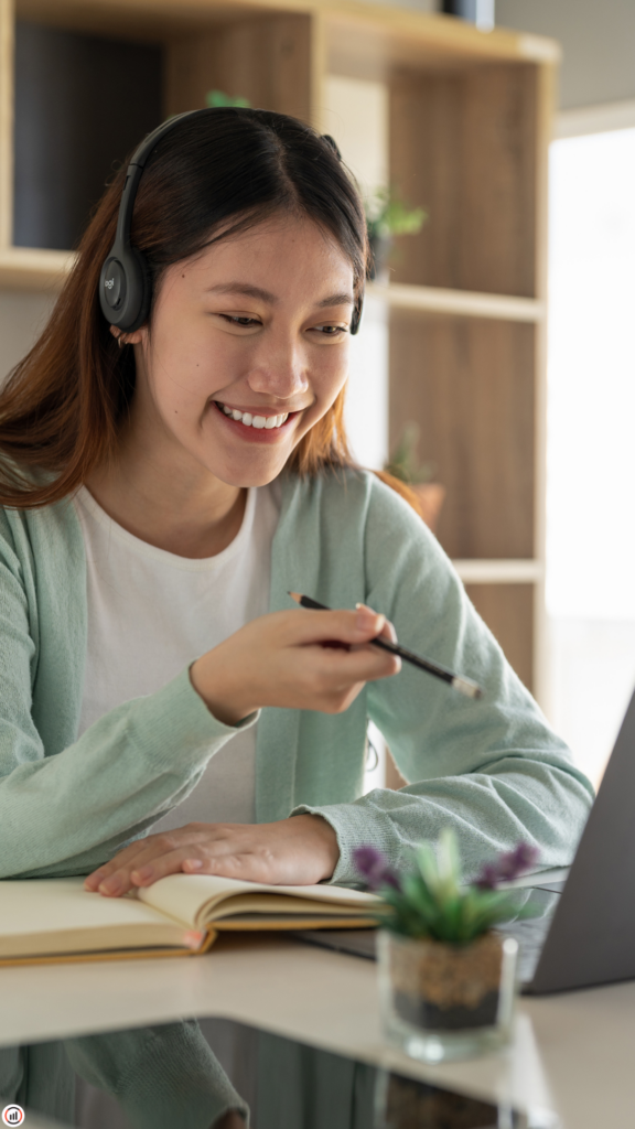 image d'une femme souriante travaillant sur son ordinateur portable avec des écouteurs au oreille .