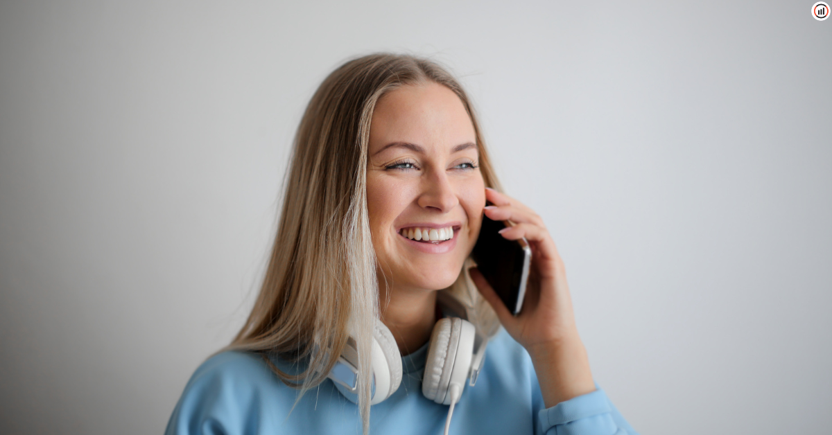 l'image d'une femme souriante au téléphone avec un casque sur le cou